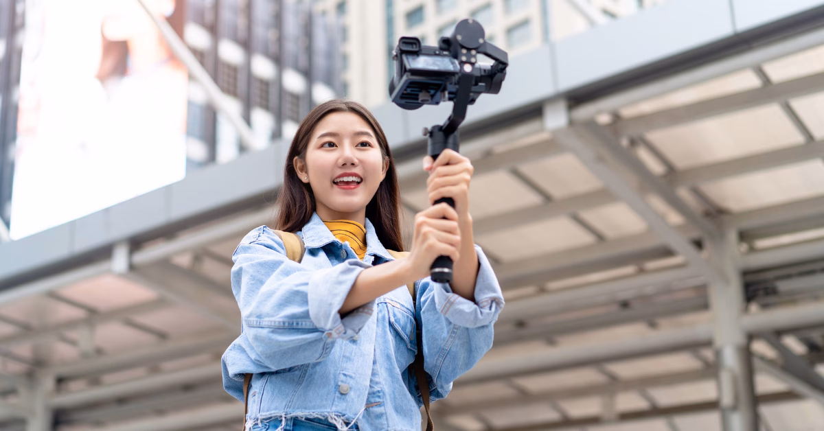 an asian female tourist doing a selfie with a professional camera in front of a hotel