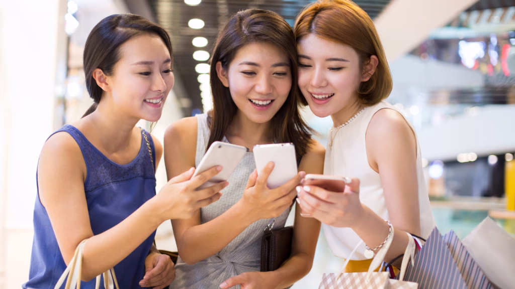 a group of female chinese friends shopping in the mall looking at a phone